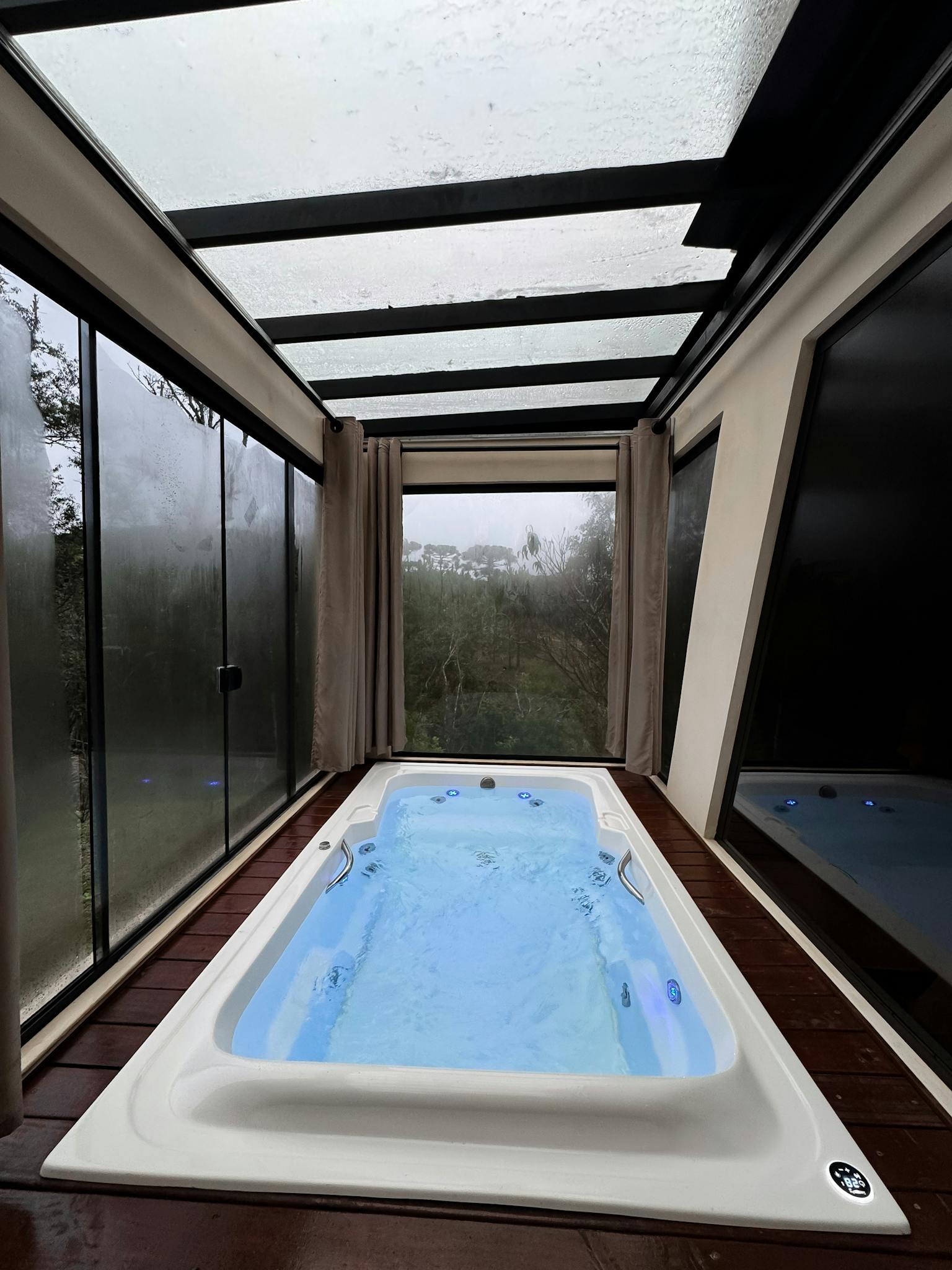 Modern indoor hot tub with glass ceiling and scenic outdoor view, perfect for relaxation.