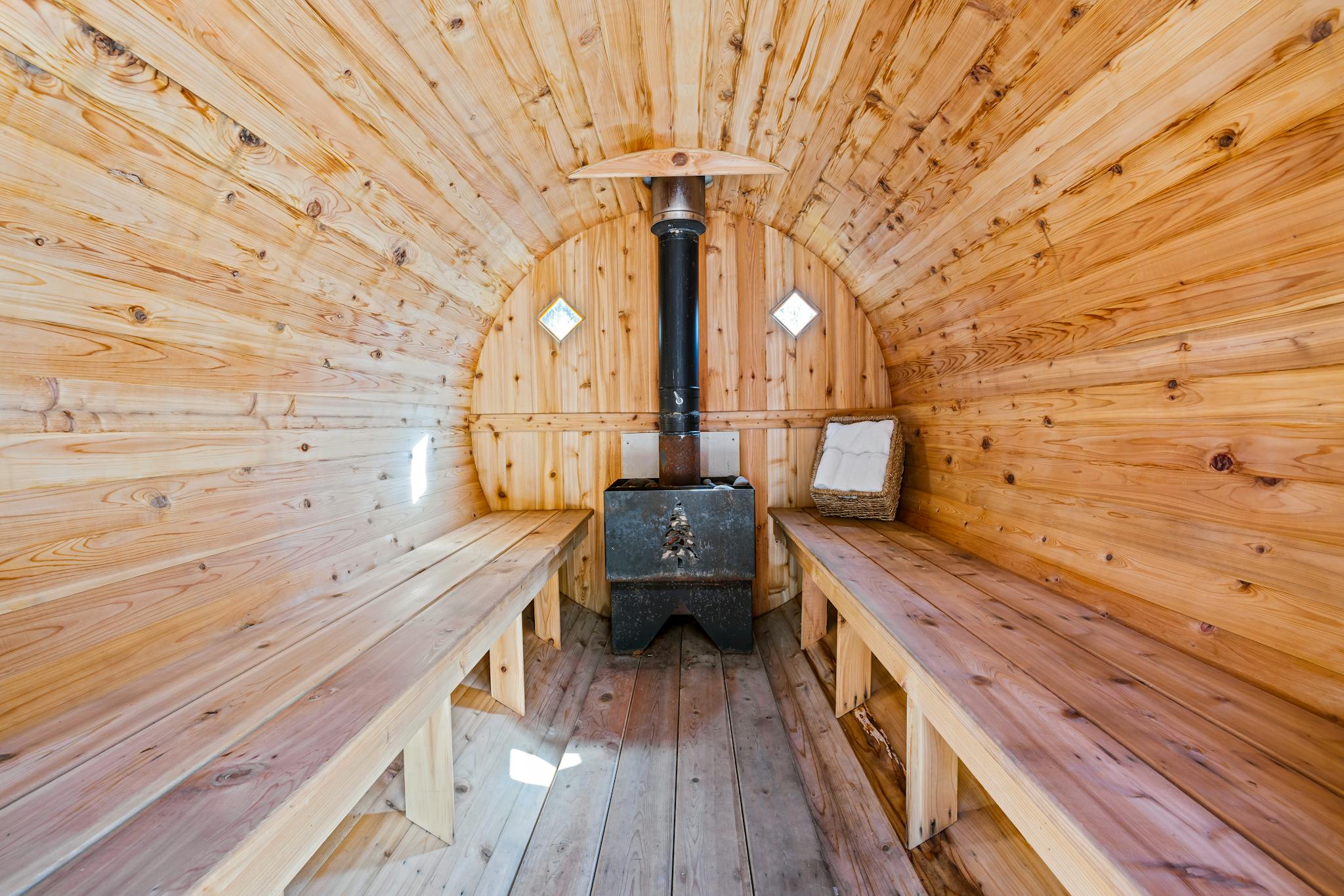 Warm wooden sauna interior design with benches and stove, ideal for relaxation.