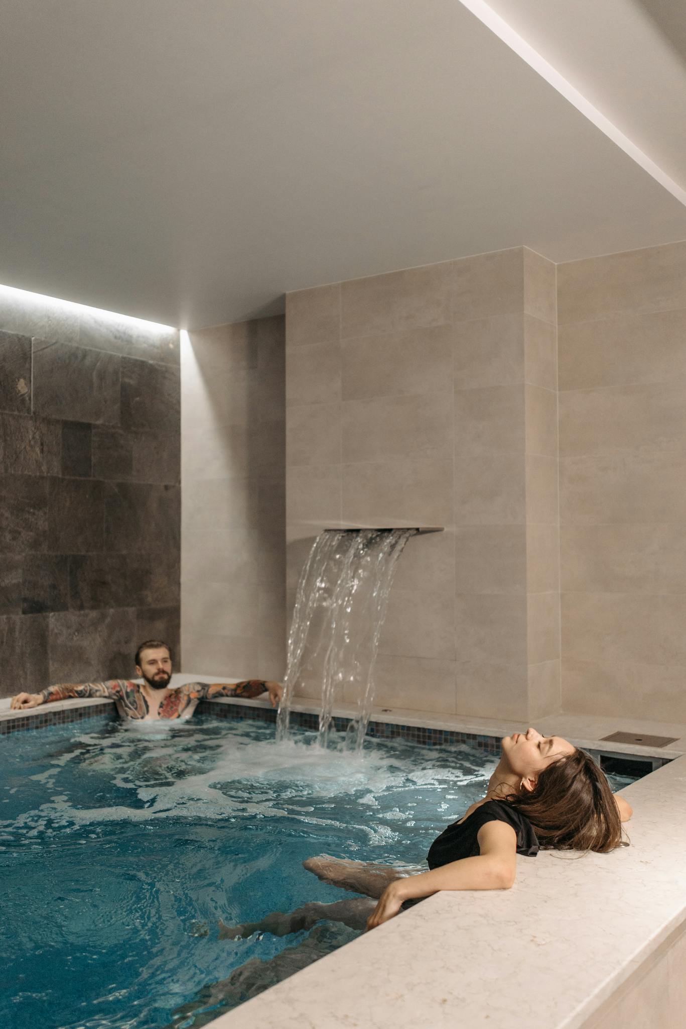 A couple enjoying a relaxing moment in a modern indoor pool.