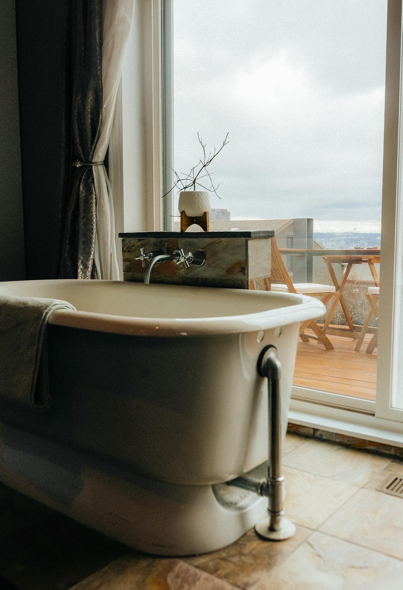 Elegant bathroom featuring a freestanding bathtub with view of outside balcony in a contemporary setting.