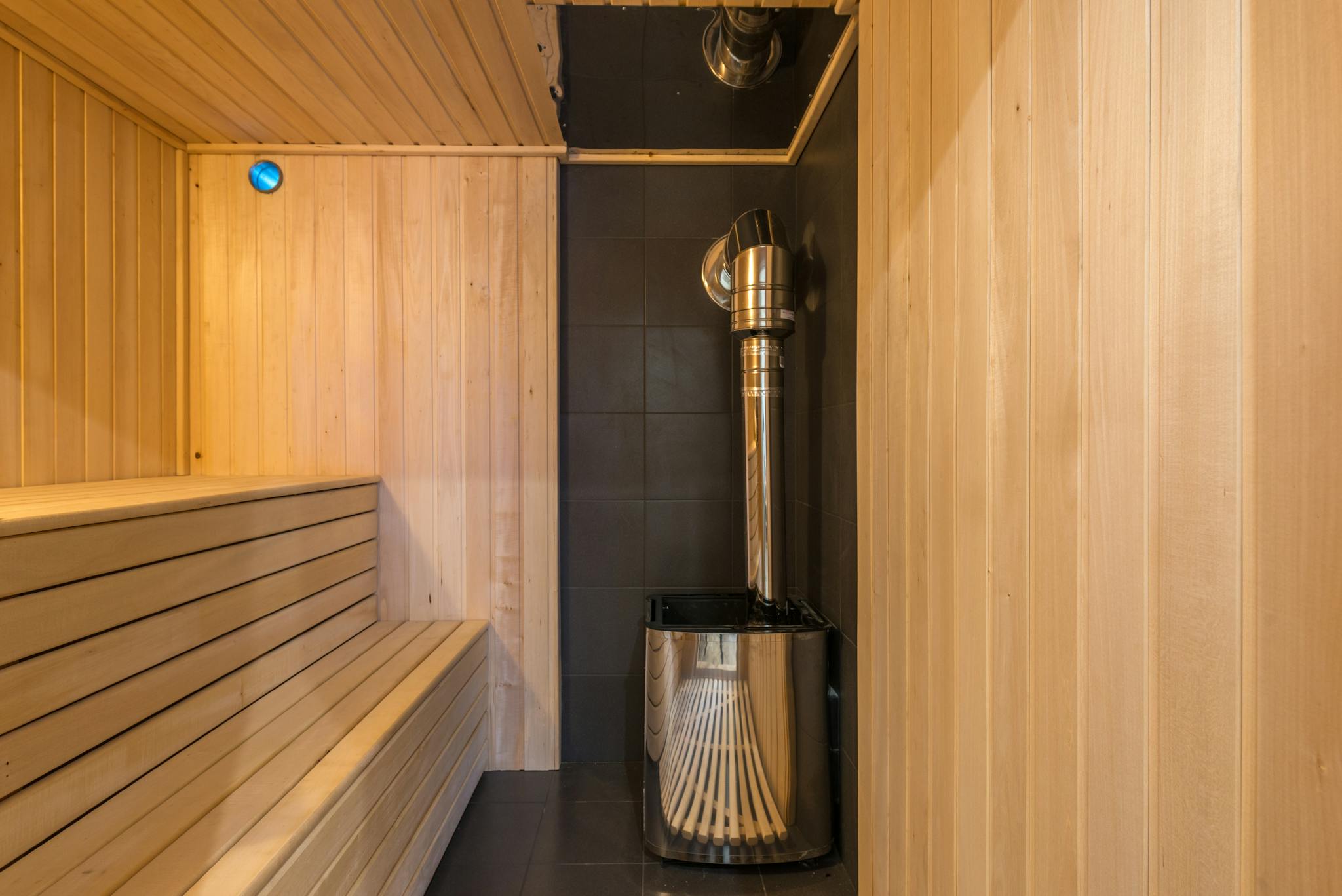 Modern wooden sauna with a sleek metal heater, showcasing luxury home interior design.