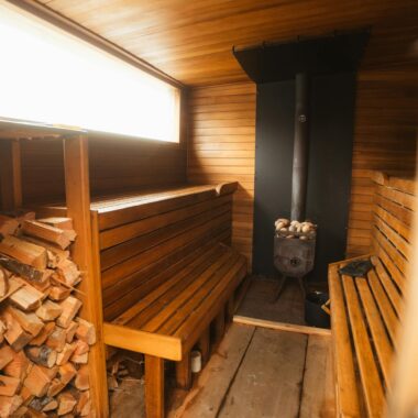 Warm wooden sauna interior with benches and fireplace, offering a relaxing and inviting atmosphere.