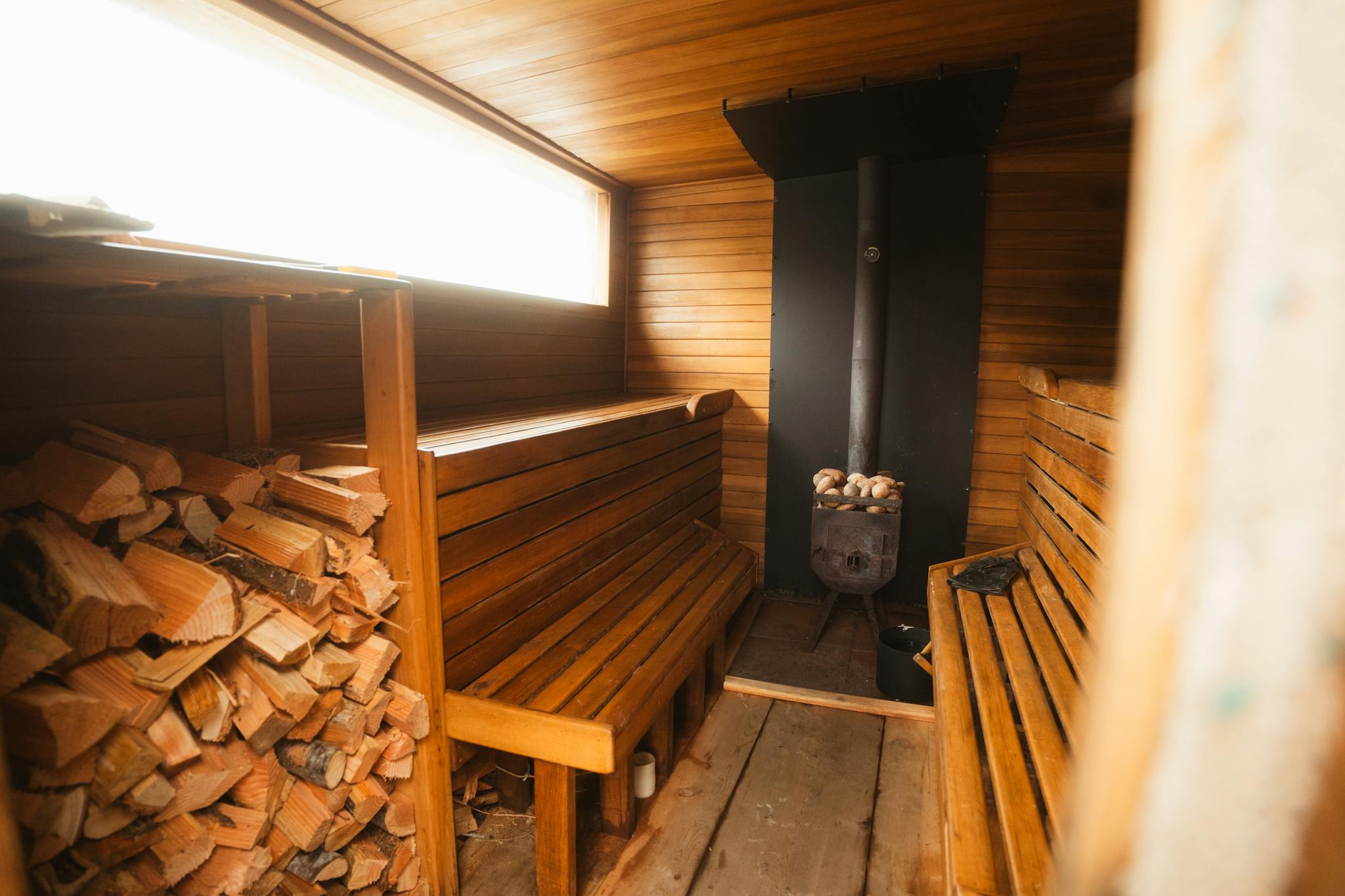 Warm wooden sauna interior with benches and fireplace, offering a relaxing and inviting atmosphere.